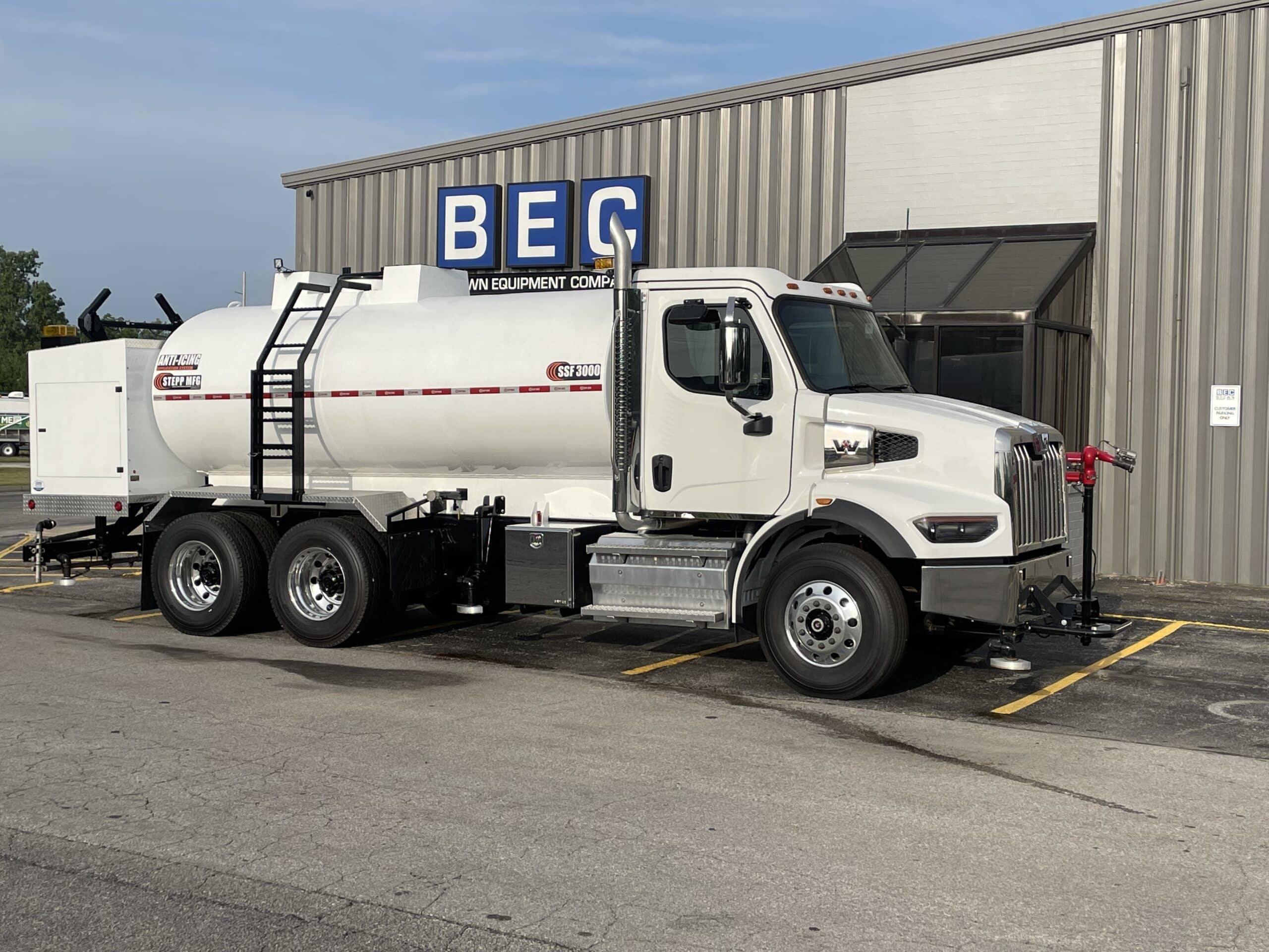 White fuel tanker truck parked outside equipment company, model STEPP-SSF-3000.