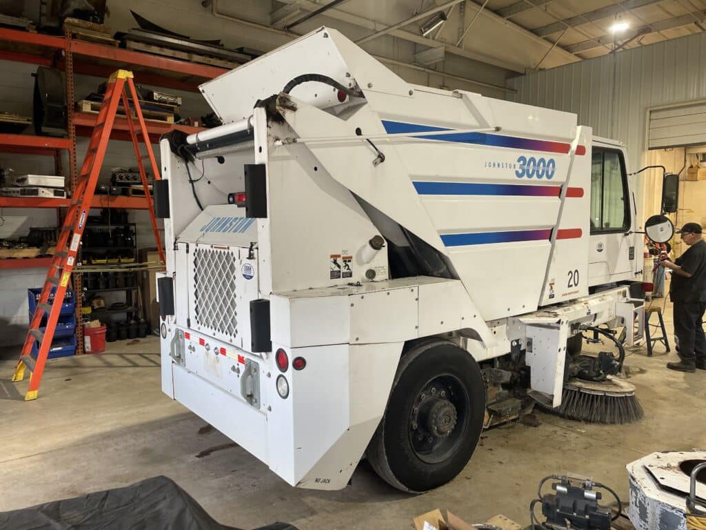 Johnston 3000 street sweeper in a workshop, ready for maintenance and cleaning tasks.