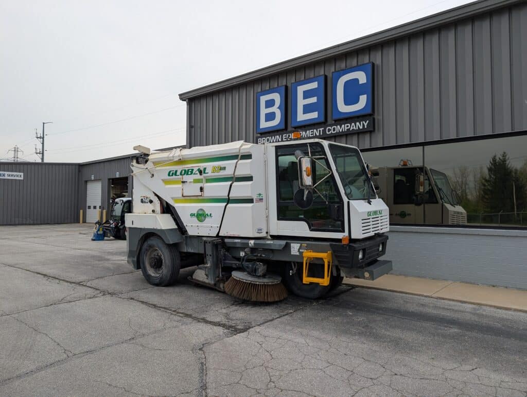 Street cleaning vehicle parked outside Brown Equipment Company, ready for service.