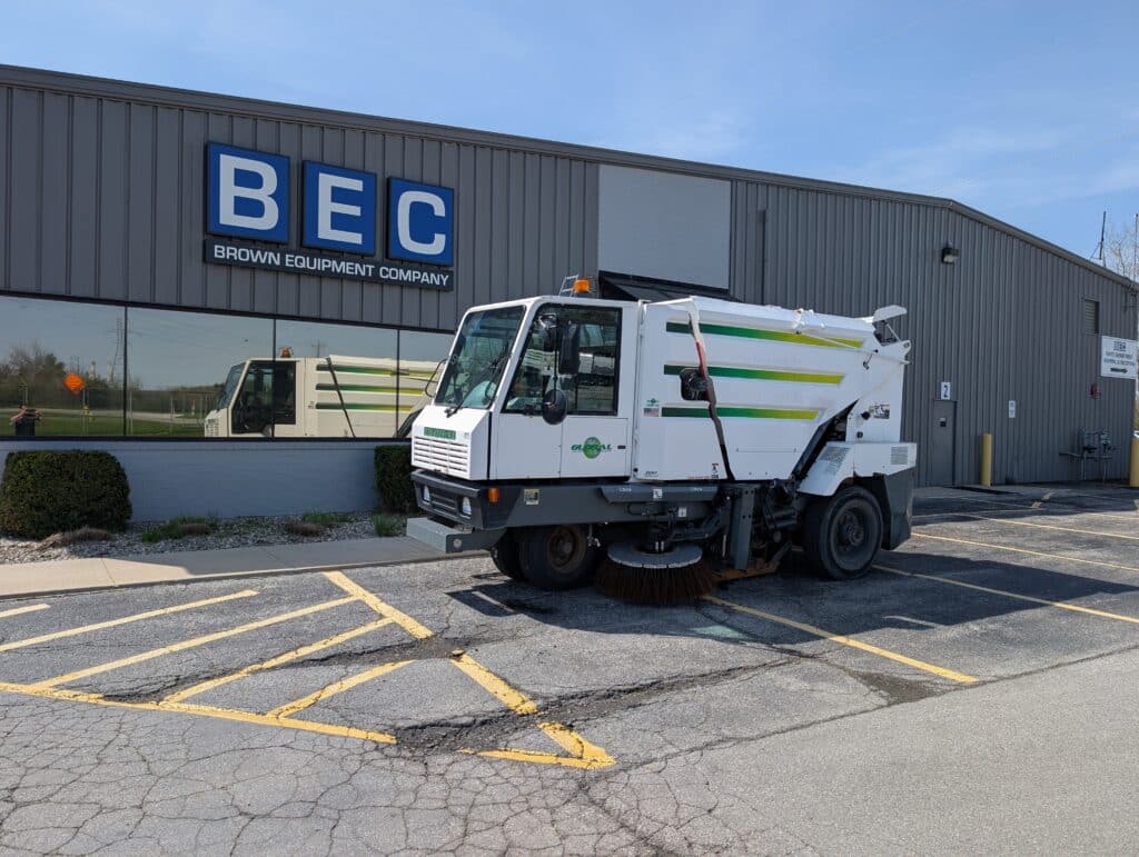 Street sweeper parked outside Brown Equipment Company facility, showcasing municipal cleaning equipment.