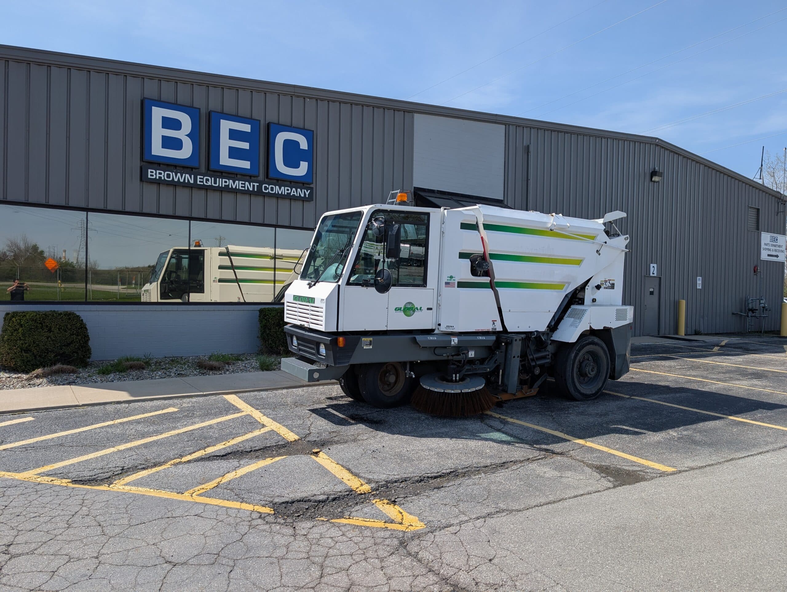 Street sweeper parked outside Brown Equipment Company facility, showcasing municipal cleaning equipment.