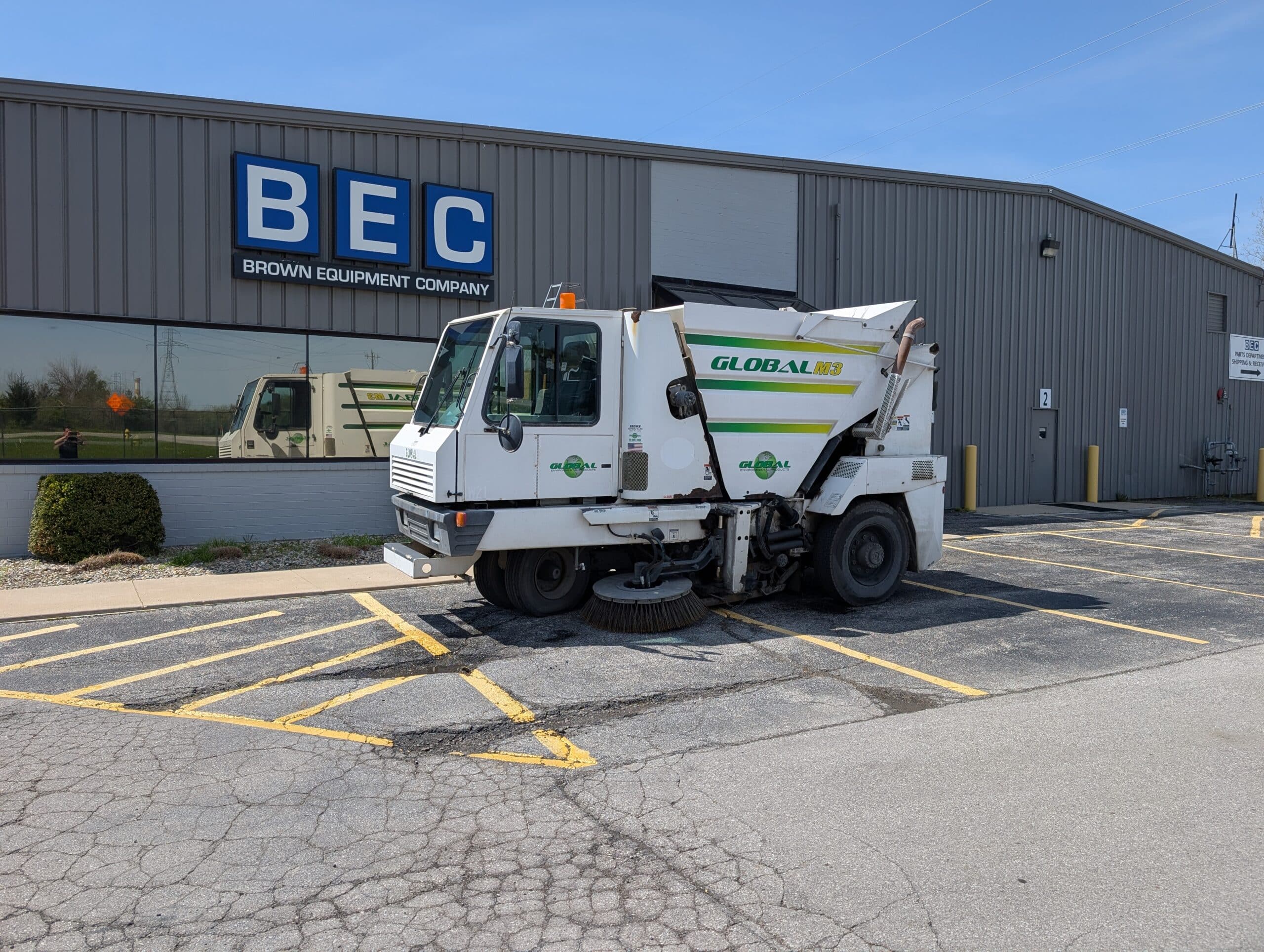 Brown Equipment Company street sweeper in front of building.