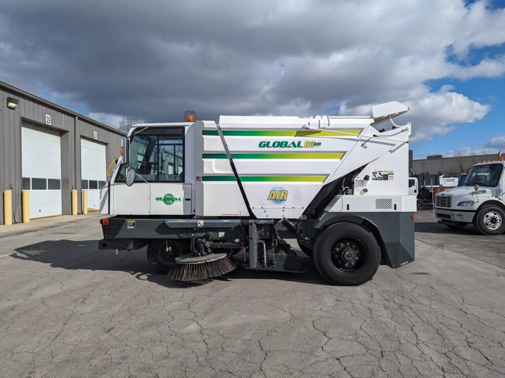 Three-wheeled street sweeper vehicle with a stainless steel hopper for effective cleaning.