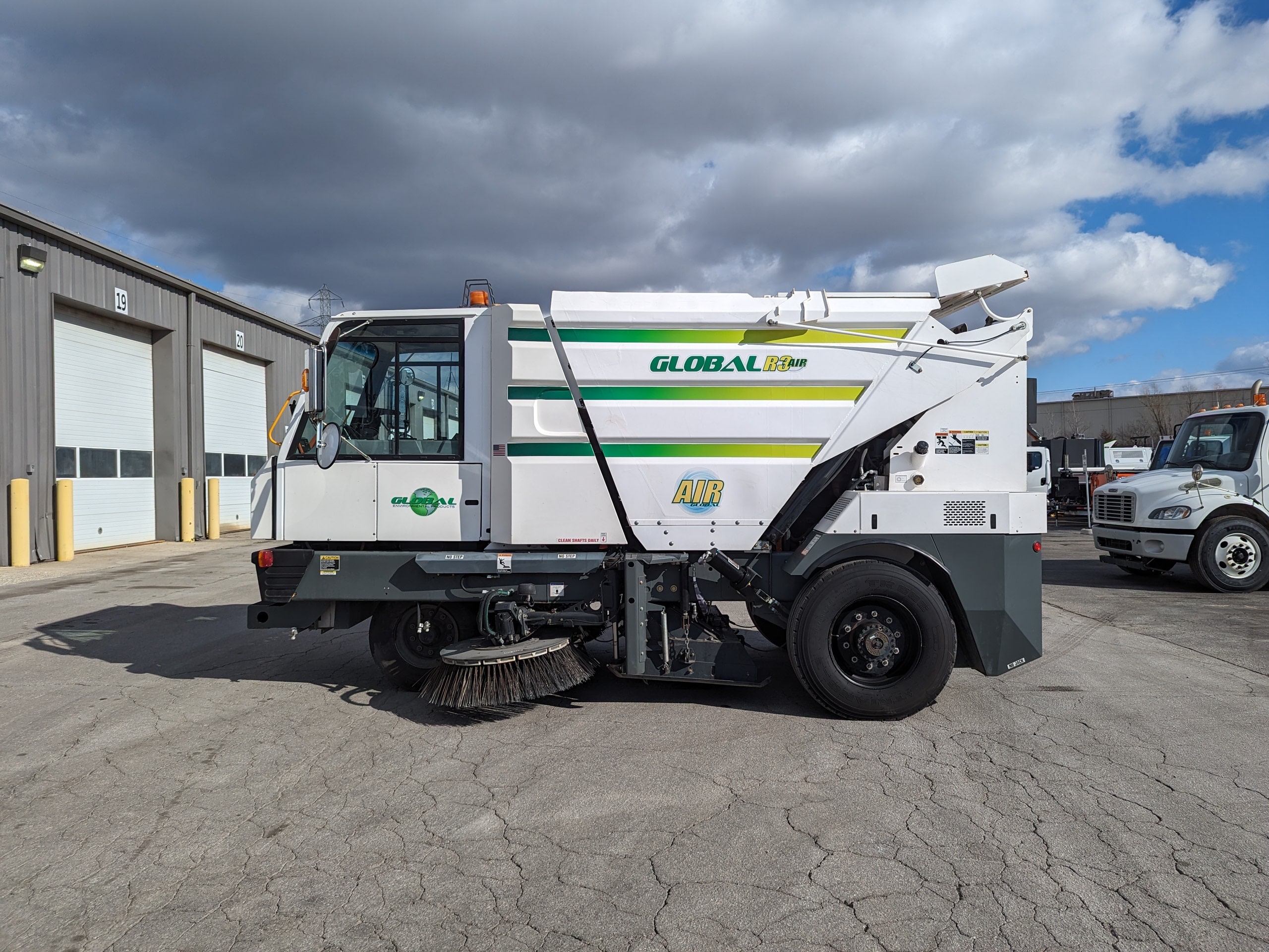 Three-wheeled street sweeper vehicle with a stainless steel hopper for effective cleaning.