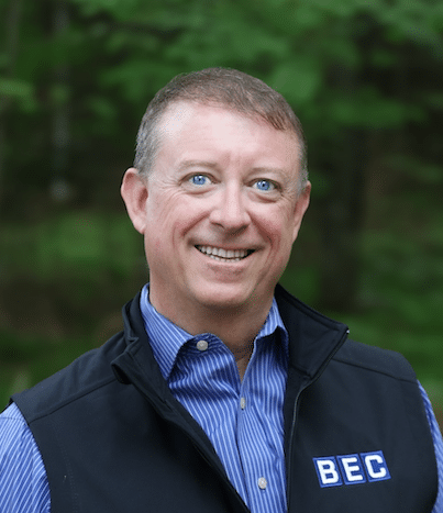 Professional business portrait showcasing a smiling man in a forest setting.
