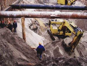 Construction site excavation showing heavy machinery and workers in action.