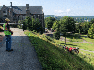 Professional landscape maintenance featuring a worker using machinery on a hillside.