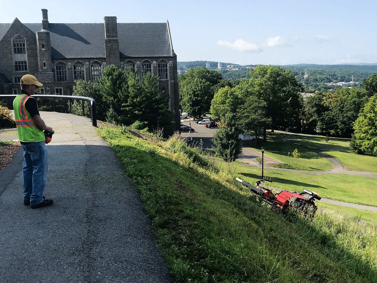 Professional landscape maintenance featuring a worker using machinery on a hillside.