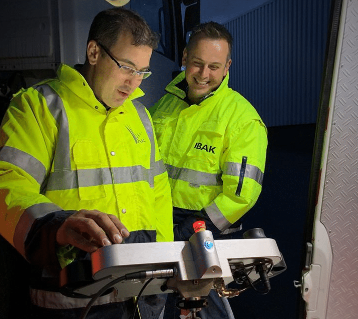Technicians working diligently with pipeline inspection equipment during nighttime operations.