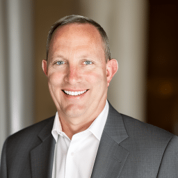 Smiling businessman in a professional suit, representing confidence and business success.