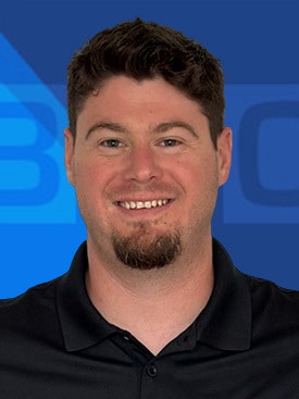 Smiling professional man in a black shirt against a blue background.