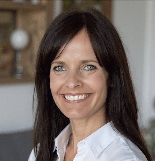 Portrait of a smiling woman with long dark hair in a bright, cheerful setting.