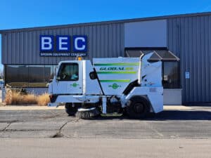 Urban street sweeper efficiently maintaining clean roadways outside a commercial building.