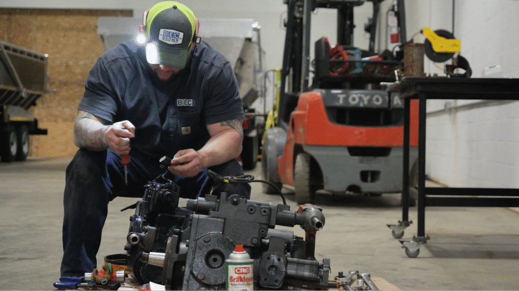 Mechanic diagnosing engine in a workshop with tools and equipment nearby.