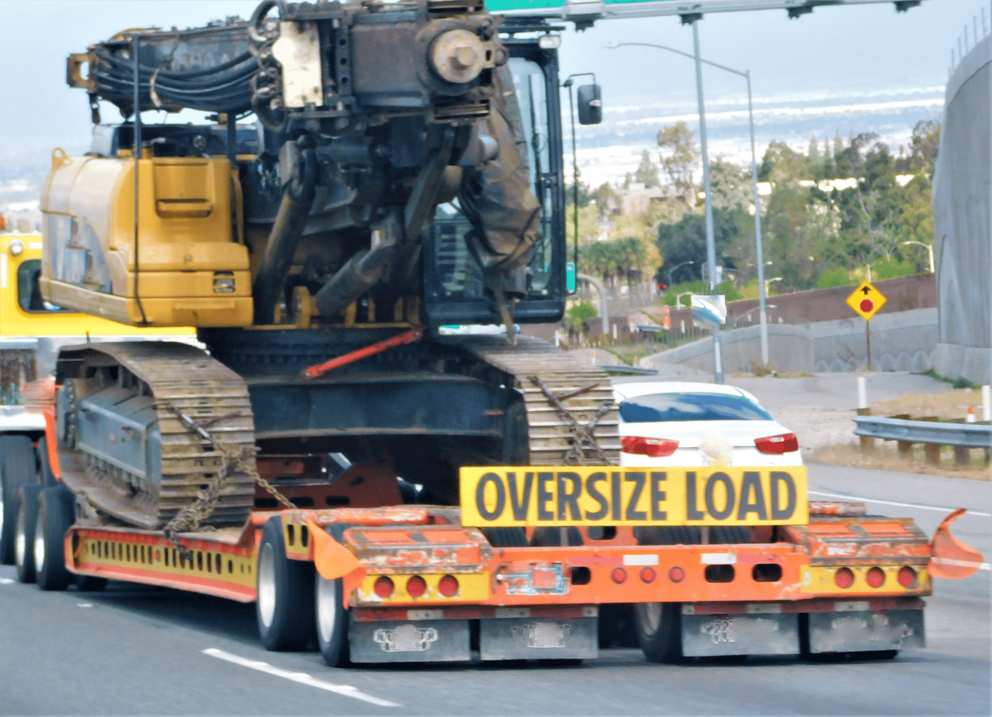 Oversized load with heavy machinery transported on a flatbed truck.