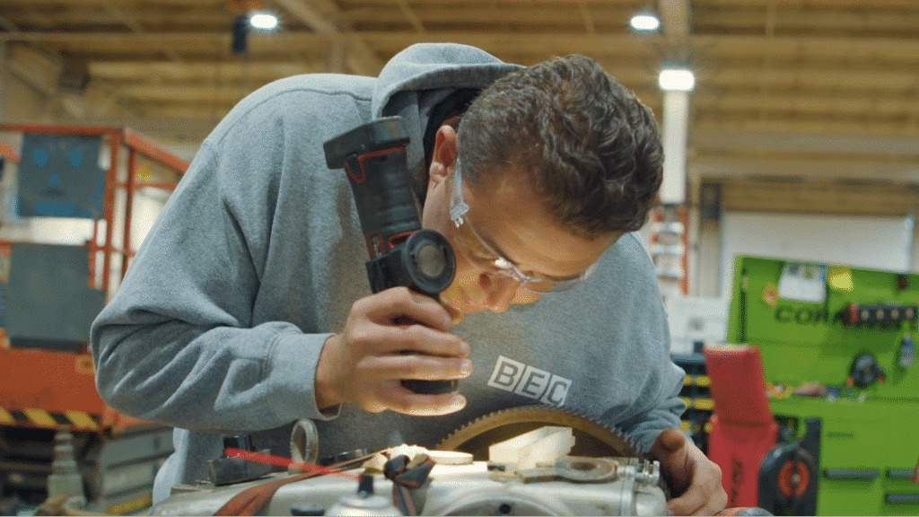Worker examining machinery for precision repairs in a modern workshop.