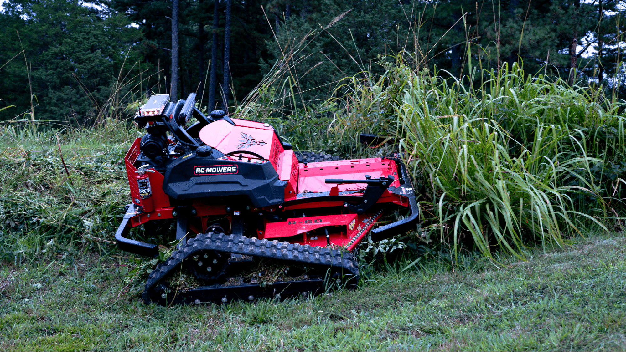 Remote-controlled mower clearing tall grass in a landscaped area.