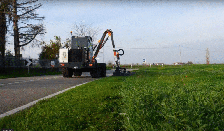 Highway maintenance vehicle trimming grass for improved visibility and safety.