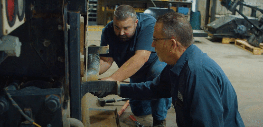 Technicians performing hands-on heavy equipment repairs in a professional workshop.
