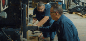 Technicians performing hands-on heavy equipment repairs in a professional workshop.