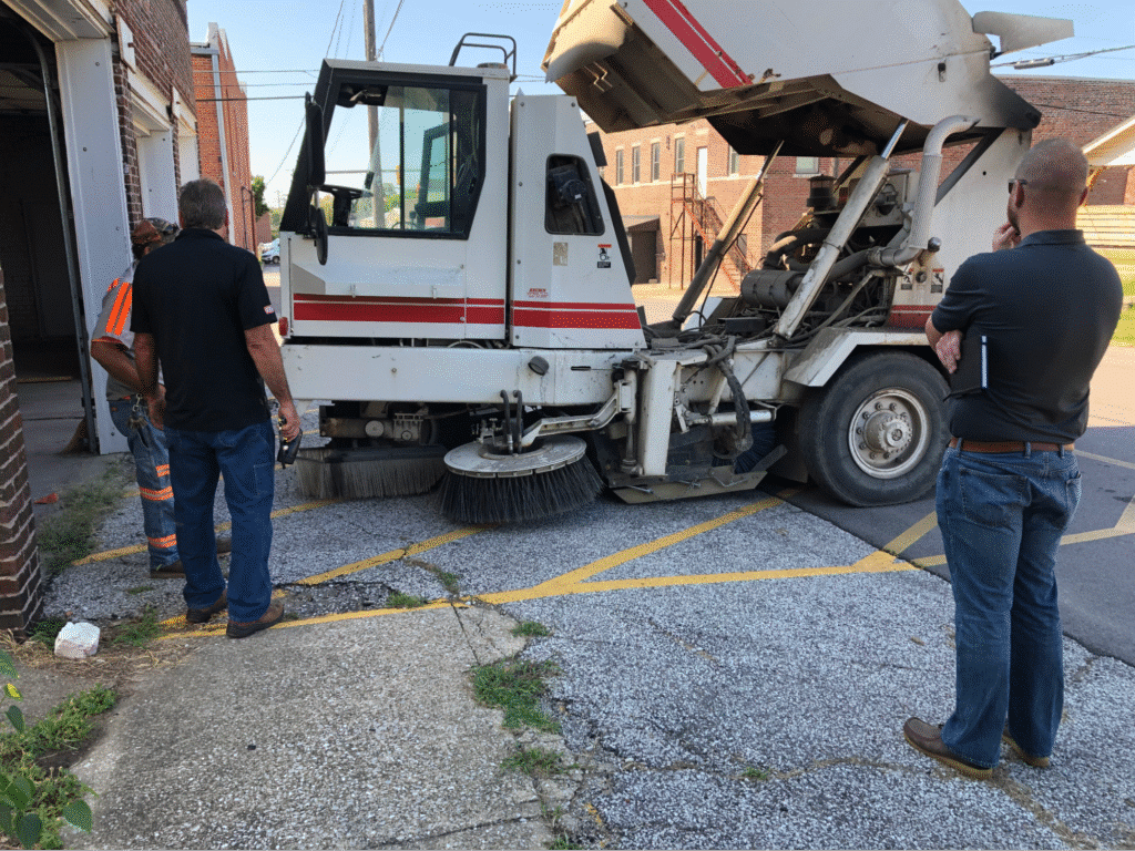 Mechanics examining a truck for repairs outside a garage.