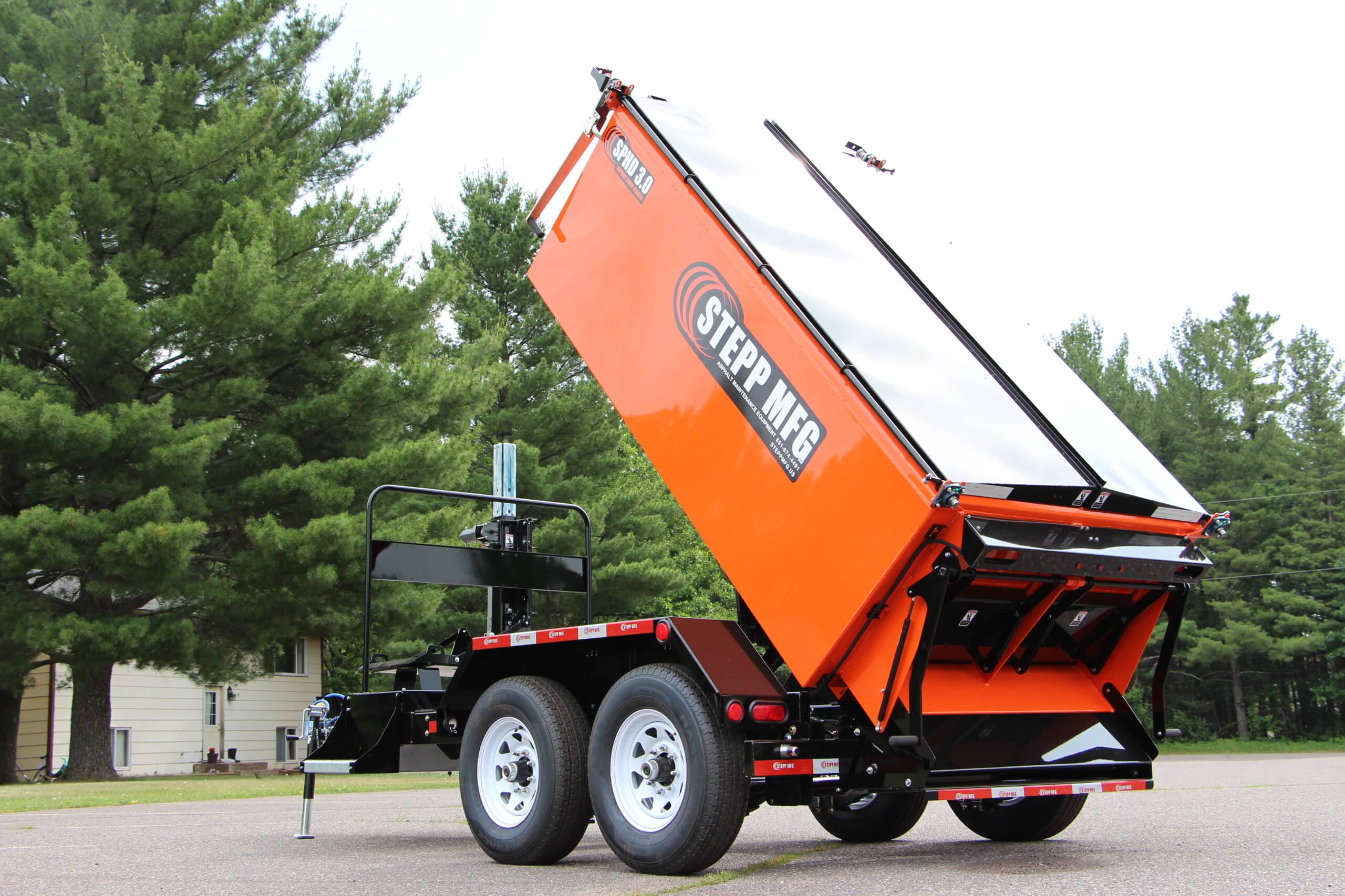 Stepp Manufacturing trailer showing hydraulic dump feature in outdoor setting.
