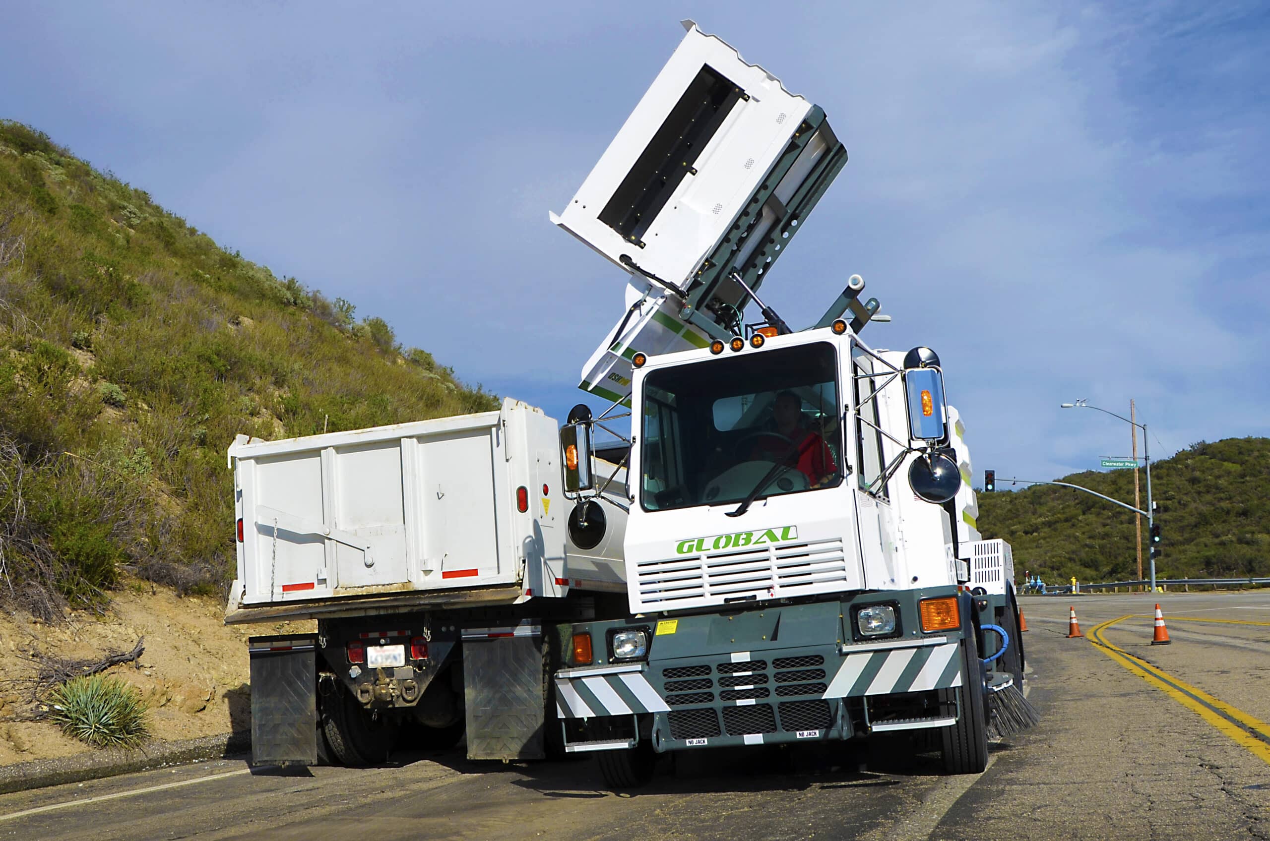 Global M4HSD street sweeper truck cleaning the road efficiently in a scenic location.