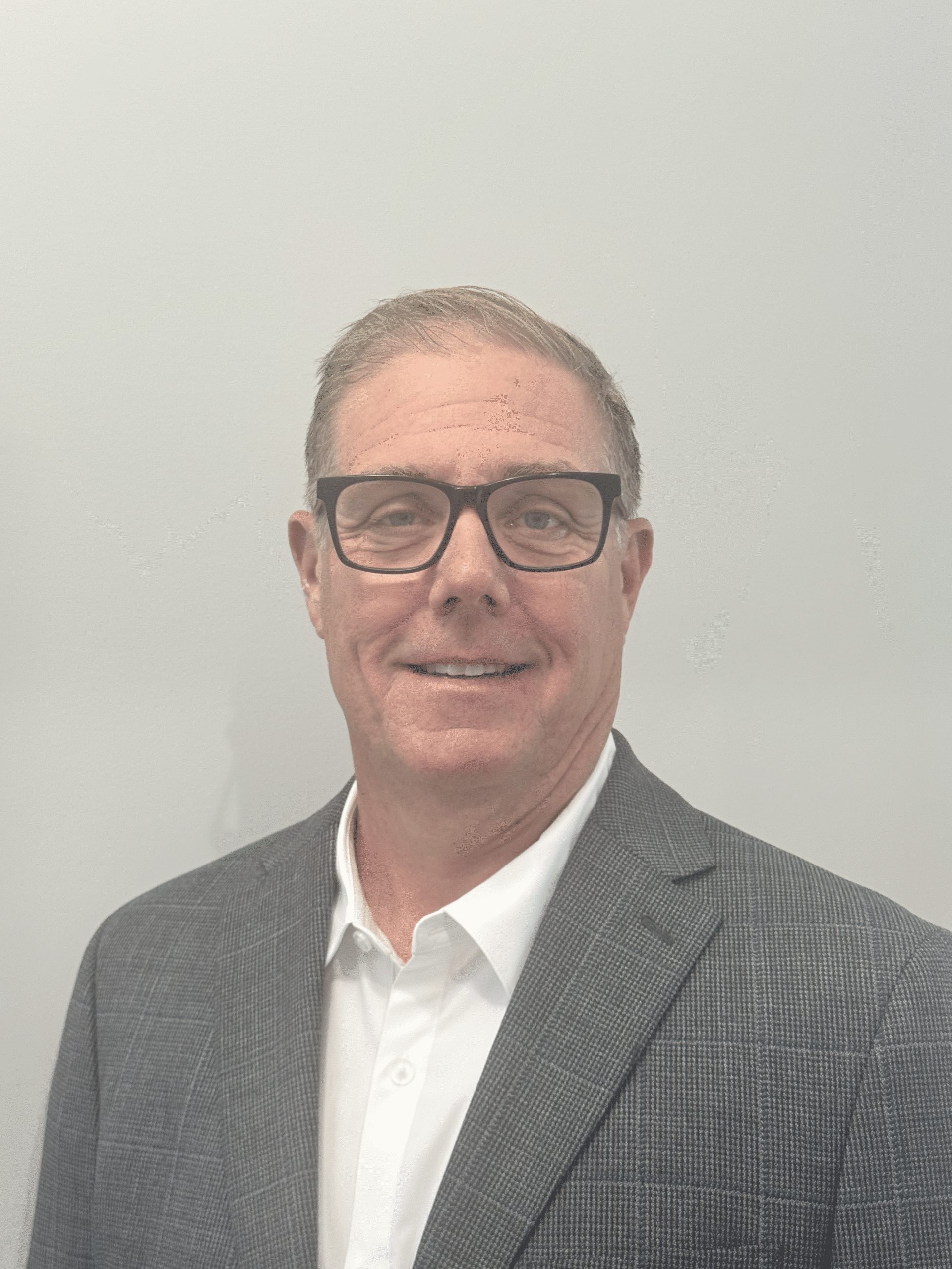 Professional business headshot of a man in a gray suit and glasses.
