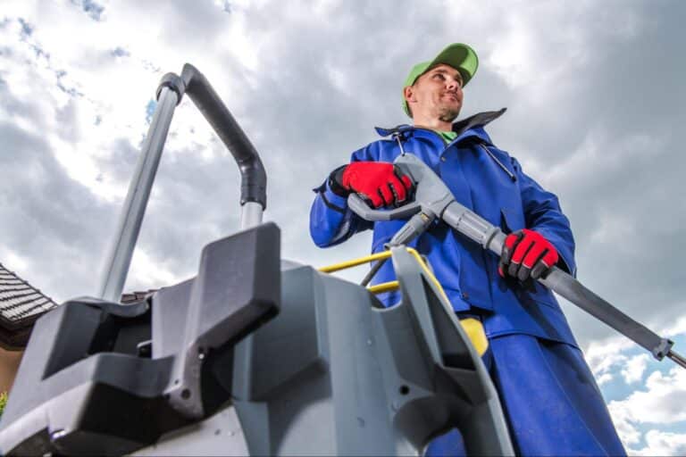 Professional cleaner using a pressure washer outdoors, ready to transform surfaces.