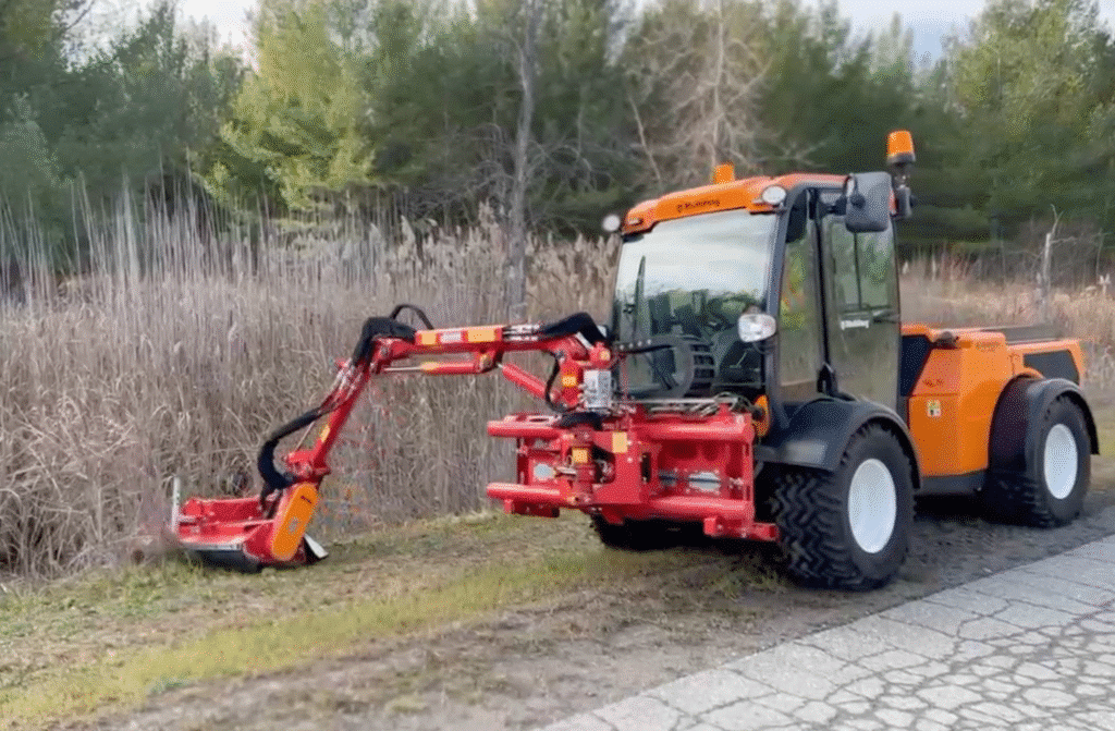 Compact utility tractor with brush cutter efficiently clearing overgrown grass along a pathway.