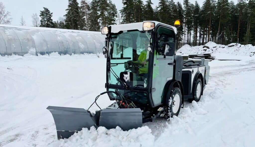 Snow plow vehicle clearing winter roads in a snowy landscape.