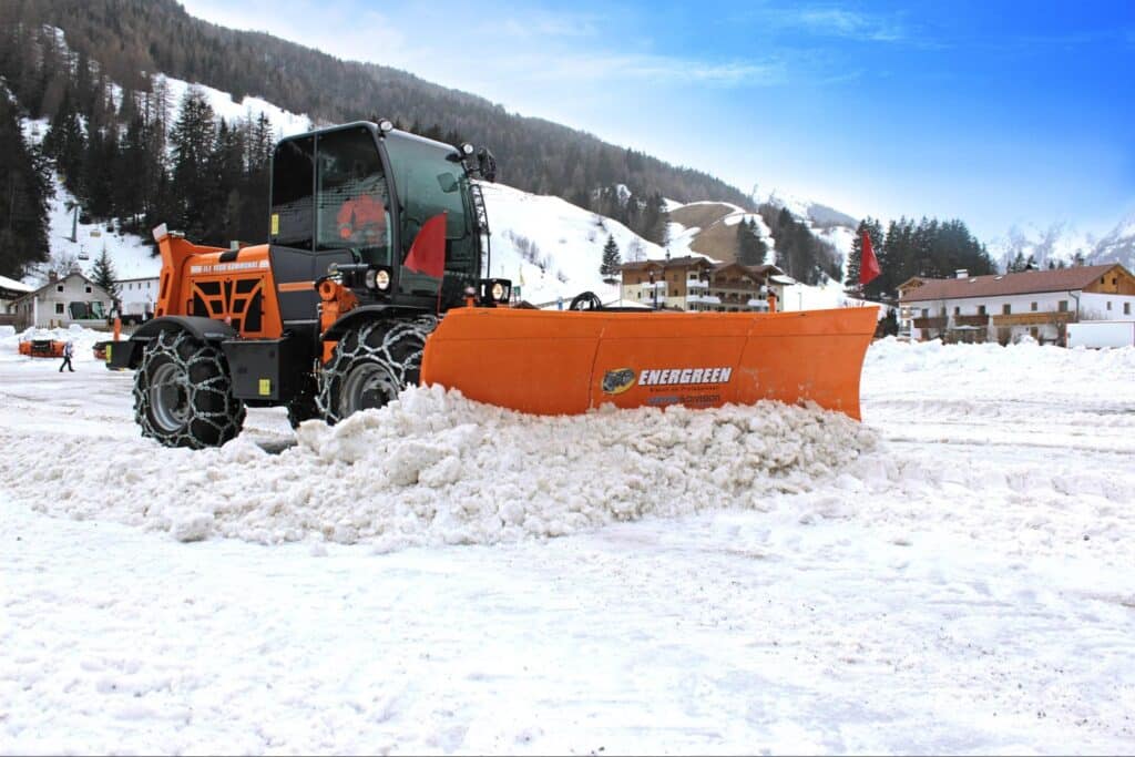 Snowplow clearing snowy roads in a picturesque winter landscape.