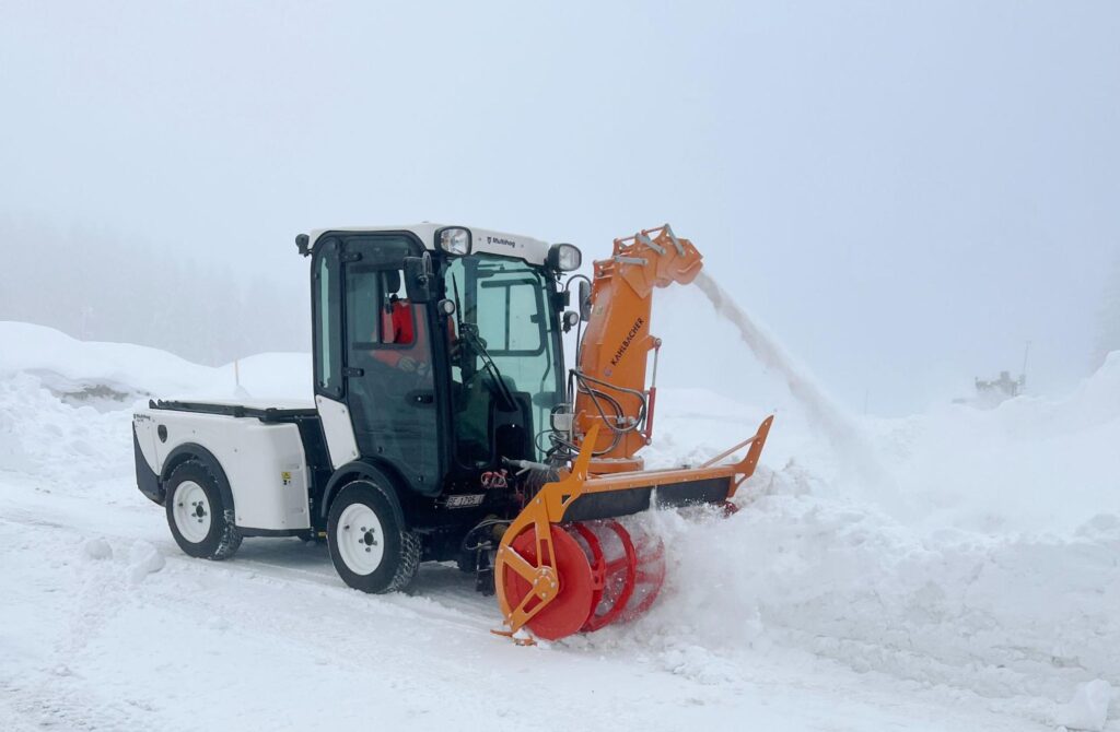 Snow plow clearing a winter road in foggy conditions.