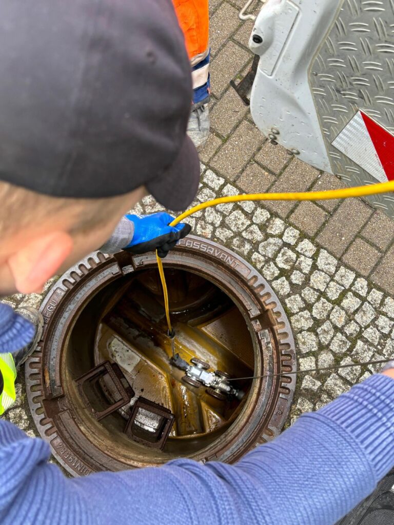 Worker inspecting sewer system with IBAK equipment for efficient drainage maintenance.