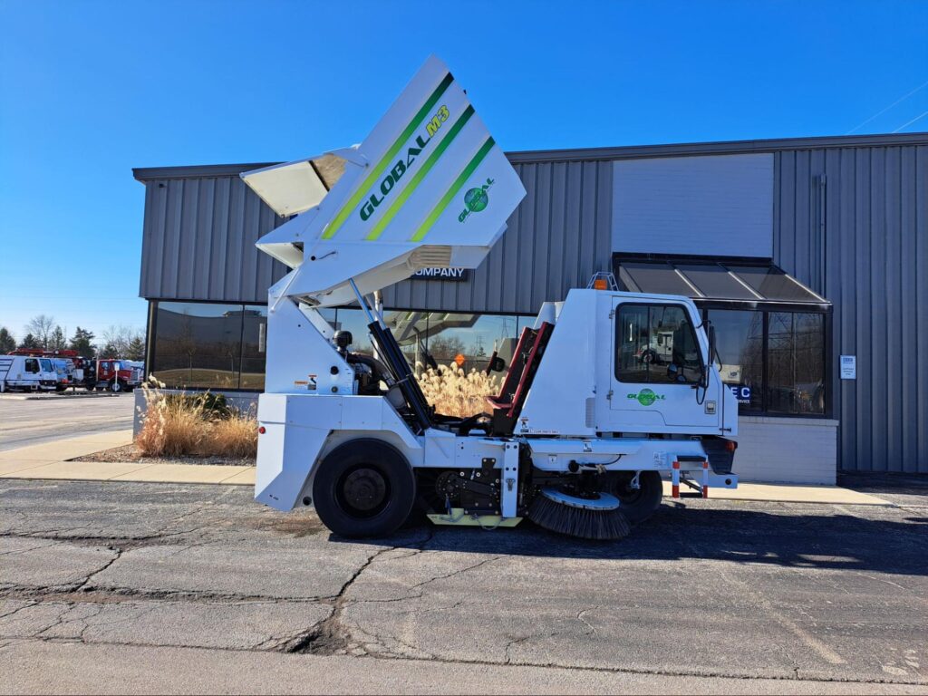 Alternative fuels for street cleaning vehicles concept with an eco-friendly street cleaning truck parked in front of dealership
