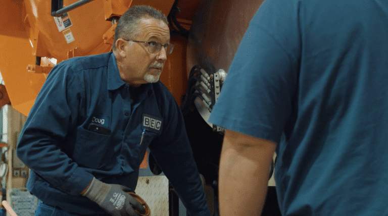 Technician inspecting equipment while collaborating with a colleague in a workshop.