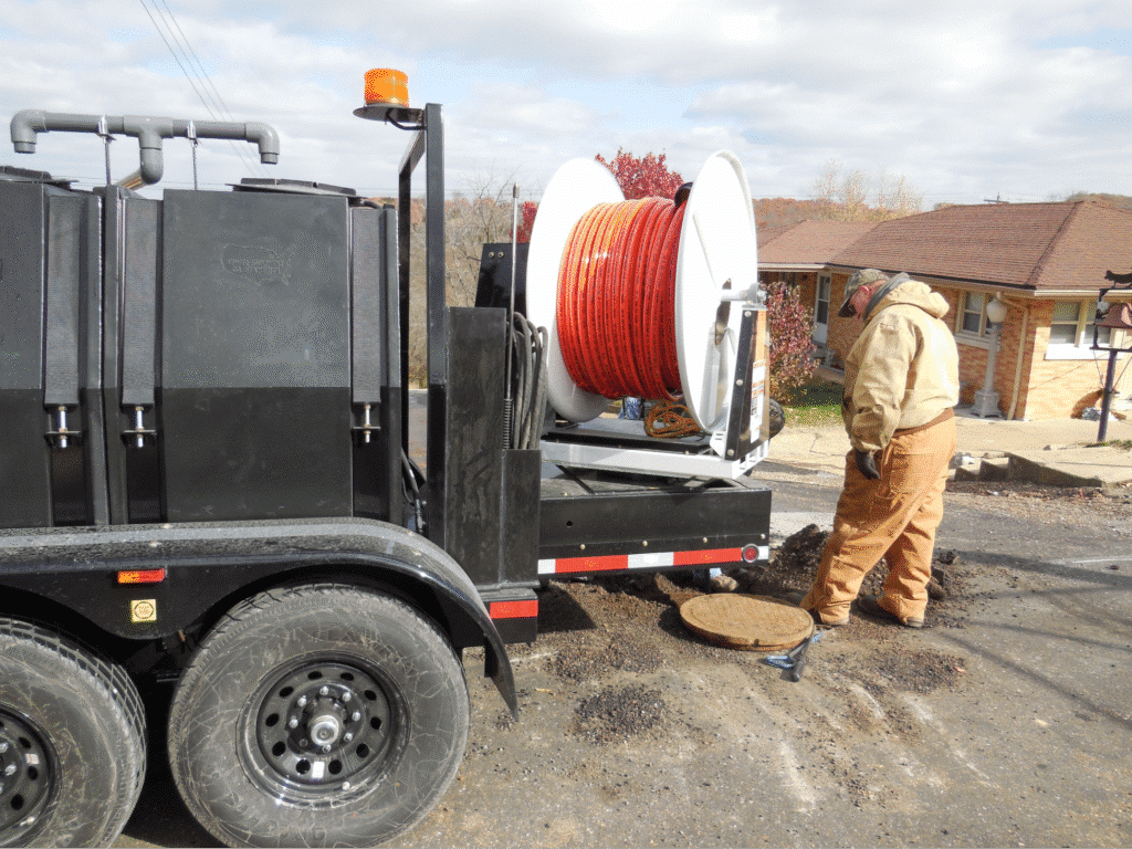 Workman operates a cable reel on a utility trailer for infrastructure repairs.