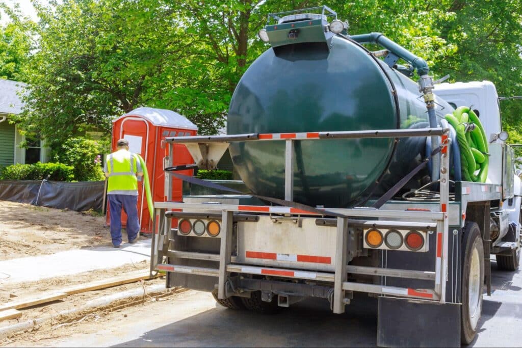 Sewer jet truck servicing a residential area with construction workers nearby.