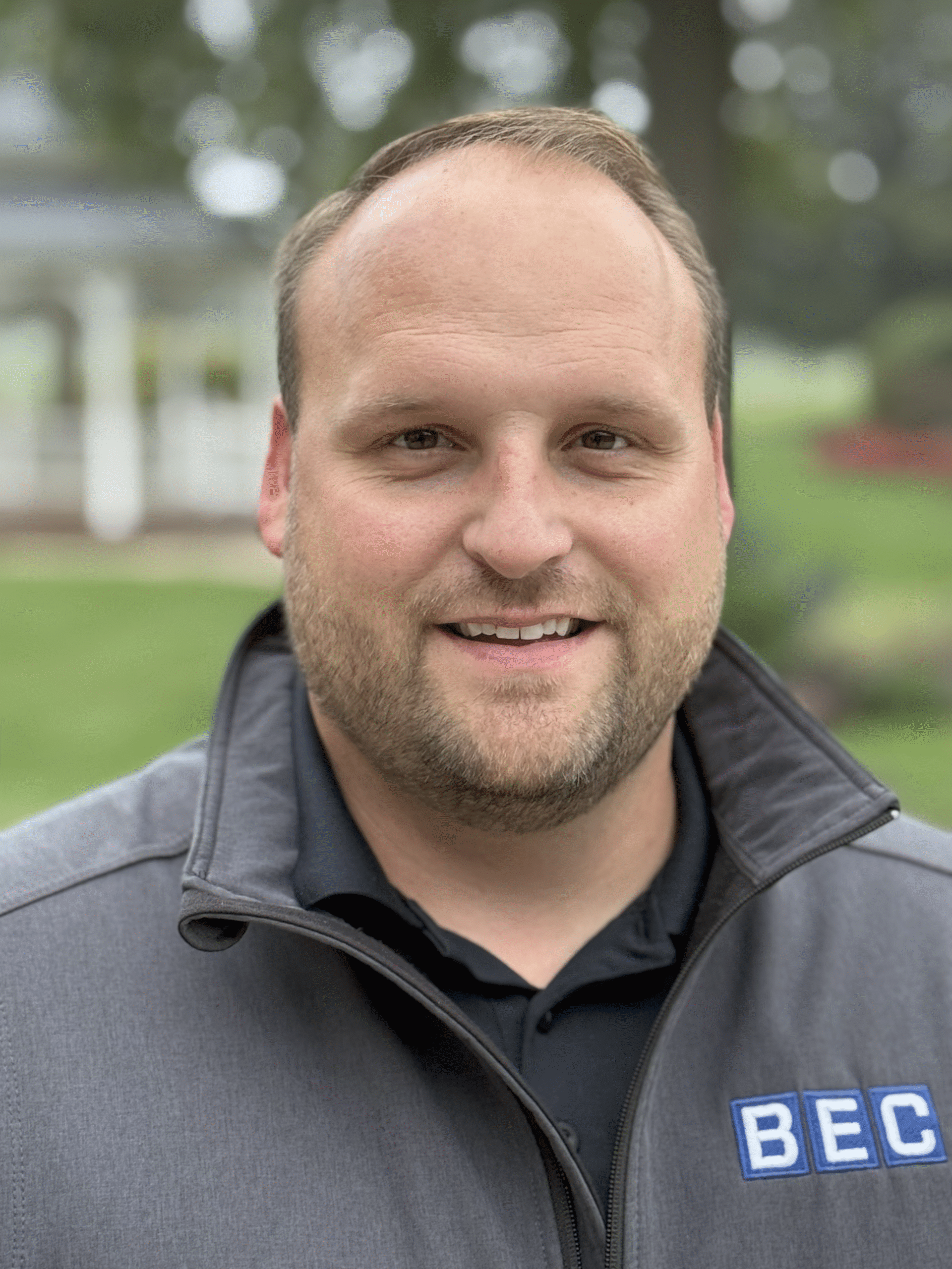 Professional portrait of BEC representative showcasing friendly demeanor and brand logo.