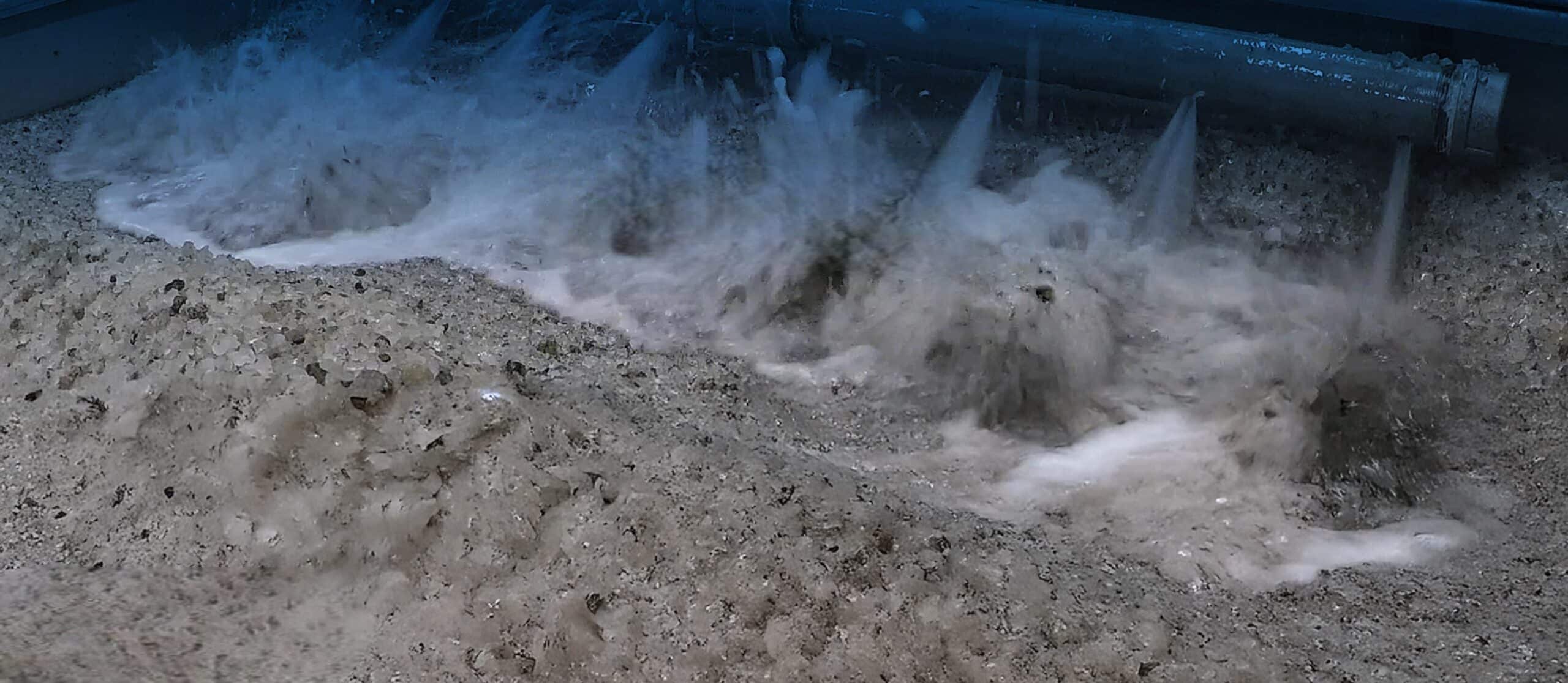 Dynamic water splashing texture with foamy waves and detailed sandy surface.
