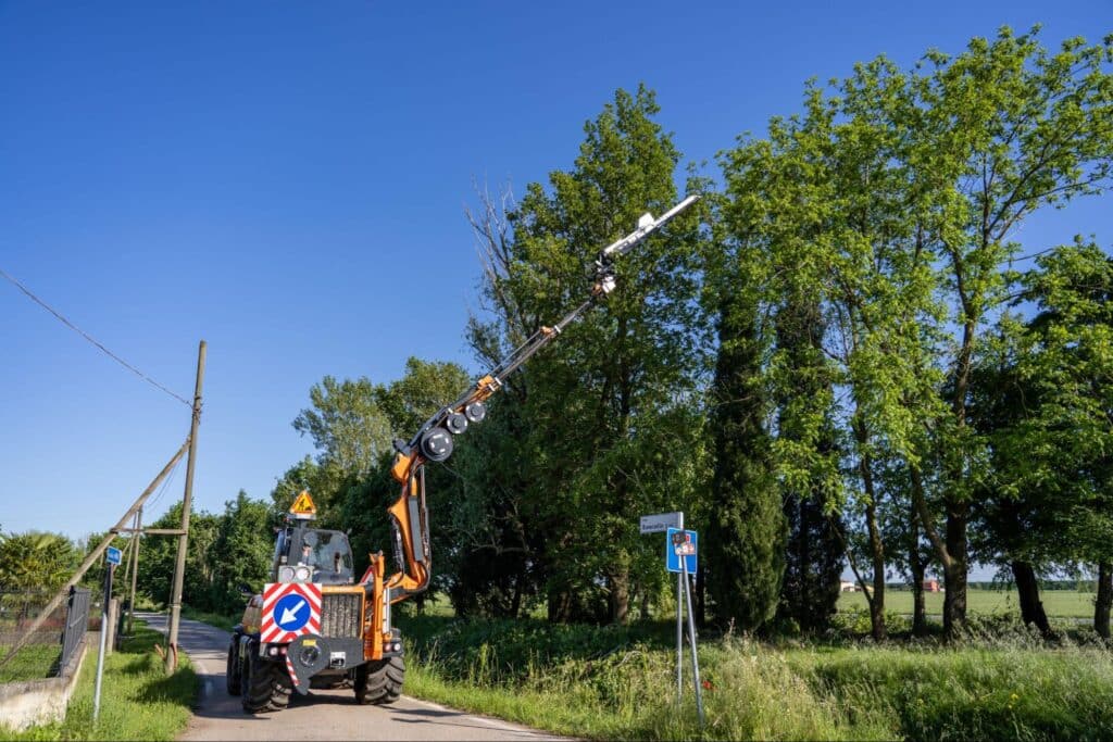 Utility vehicle working on power lines surrounded by trees on a sunny day.