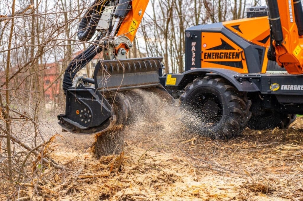Heavy-duty forestry equipment clearing brush and debris in a wooded area.