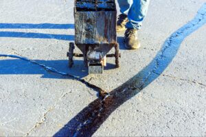 Applying sealant to asphalt cracks for long-lasting pavement repair.
