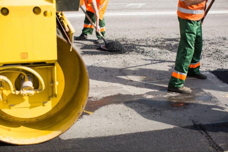 Workers applying fresh asphalt on a road construction site.
