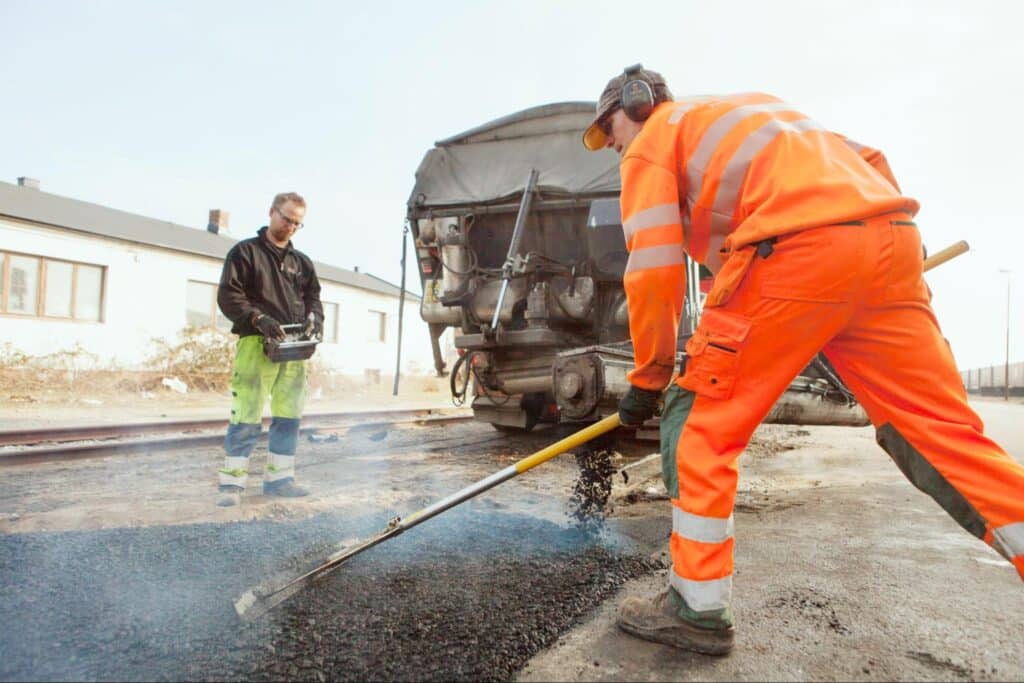 Asphalt repair crew working on a road at a construction site.