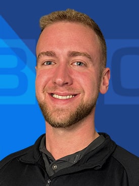 Professional portrait of Jarrett Phillippe in a black jacket against the blue BEC background.
