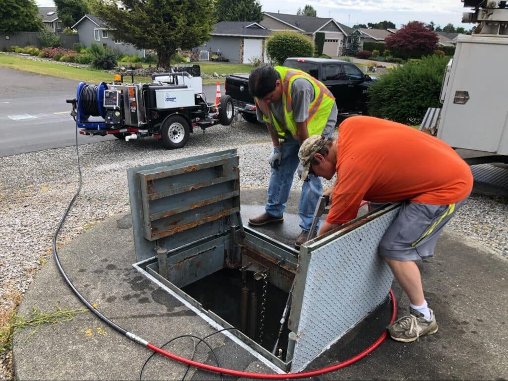 Sewer maintenance workers servicing a residential sewer access point for efficient drainage.