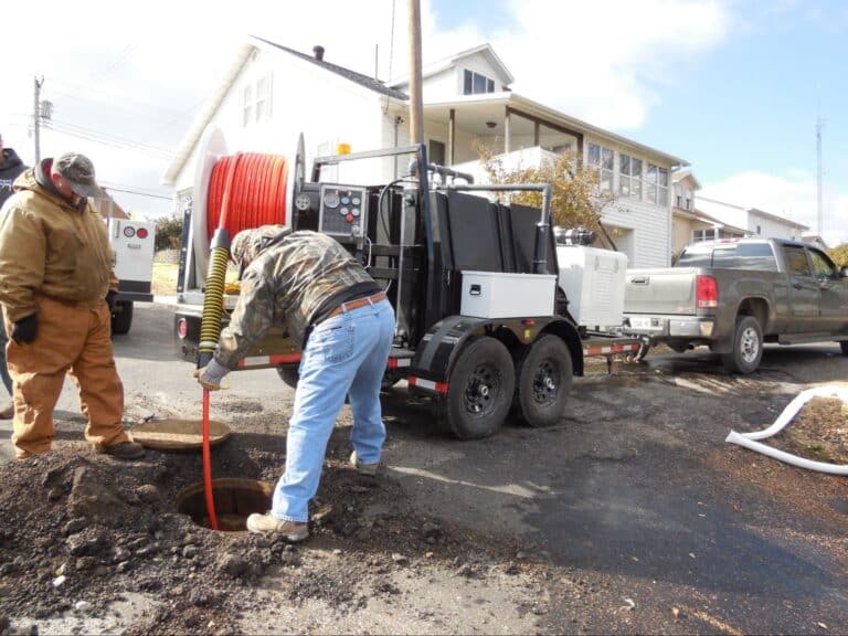 Sewer repair crew fixing pipes on a residential street.