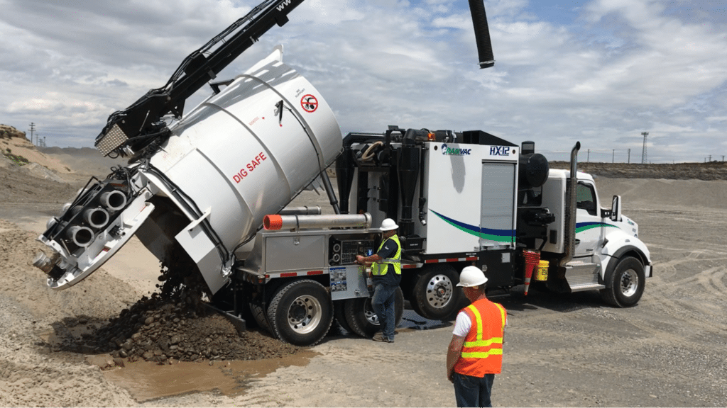 Hydro excavator operating at a construction site with workers in safety gear.