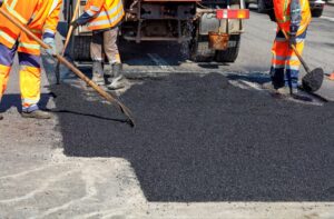 Road crew applying fresh asphalt for smooth road surface repair.